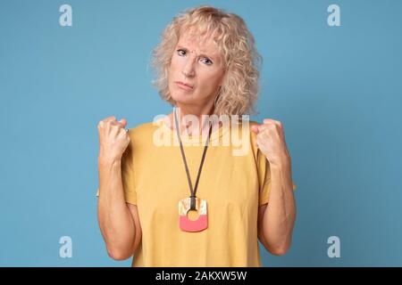Une vieille femme en colère qui prépare les poings à se défendre sur fond bleu Banque D'Images