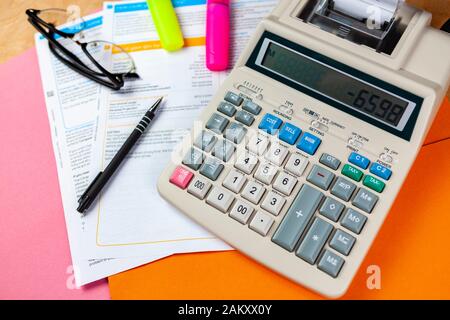 Calculateur d'impression multifonction sur un bureau de comptables avec surligneurs et une paire de lunettes Banque D'Images