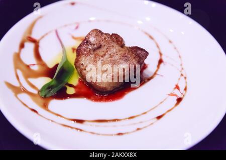 Délicieux gras frais en tranches, poêlé avec sauce aux baies servis sur une plaque en porcelaine blanche. Foie De Canard Ou D'Oie Engraissé Comme Nourriture Française Banque D'Images