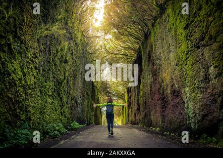 La femme marche seule dans un beau cadre naturel avec des bras ouverts en profitant de la liberté et de la nature. Les touristes de fille marchant sur le chemin entre deux murs de roche W Banque D'Images