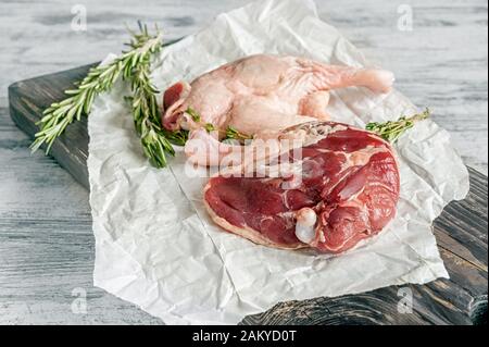 Pieds de canard crus. La viande de volaille est prête à cuire sur papier et un tableau de découpe en bois. Banque D'Images