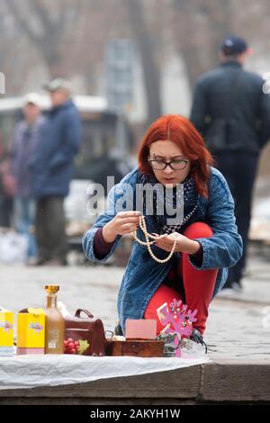 Un acheteur inspecte un collier sur un marché de rue dans le centre de Lviv, en Ukraine. Banque D'Images