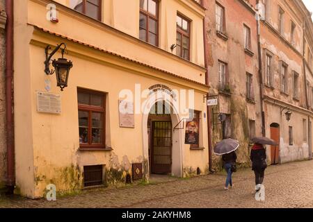 Les visiteurs traversent la pluie protégée par des parasols dans la vieille ville de Lublin, en Pologne Banque D'Images