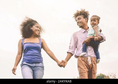 Une famille africaine heureuse s'amuser dans le parc public - mère de père et petite fille profitant de temps en plein air et en riant ensemble Banque D'Images