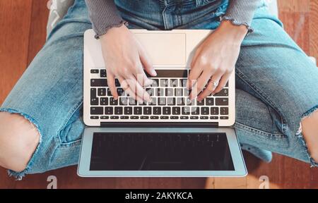 Jeune fille utilisant un ordinateur portable à la maison - Femme ayant du plaisir avec un nouvel ordinateur de technologie tout en étant assis sur le sol - Personnes, jeunes , technologie et concept de travail Banque D'Images