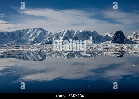 Canal Lemaire vu par un jour ensoleillé avec montagnes, glaciers et glace reflétées dans l'océan, Antarctique Banque D'Images