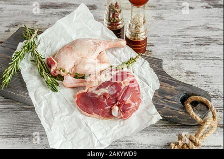 Pieds de canard crus. La viande de volaille est prête à cuire sur papier et un tableau de découpe en bois. Banque D'Images