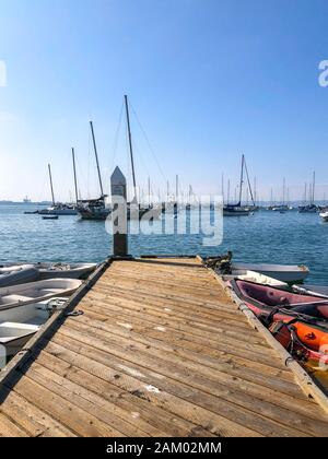 Petite jetée en bois avec petit bateau abandonné et bateau à voile sur l'arrière-plan pendant la journée du ciel bleu à San Diego, Californie, États-Unis 22 novembre 2019 Banque D'Images