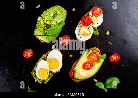 Toasts de patate douce avec avocat, œufs durs, tomates et graines de sésame sur fond sombre. Concept de repas sain. Cuisine propre, plats du Pescetarian, vue sur le dessus Banque D'Images