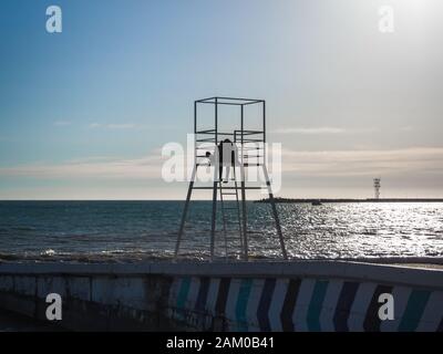 Silhouette d'un couple affectueux sur la tour du maître-nageur sur la plage Banque D'Images