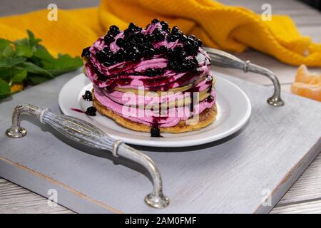 Les crêpes ont servi de la crème avec du fromage cottage et des bleuets sur un beau plateau en bois, à côté de la confiture de bleuets et de la menthe, beau fond, vue latérale Banque D'Images