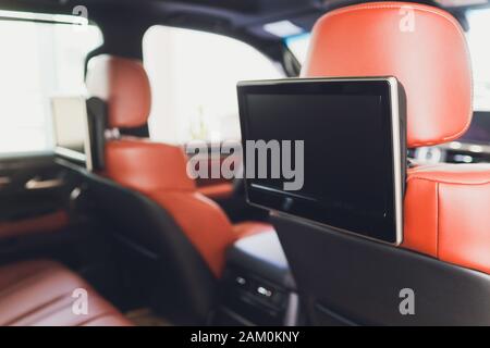 Voiture à l'intérieur. Intérieur d'une voiture moderne de prestige. Sièges arrière avec écrans, tables téléphone portable. Le cockpit blanc avec lumière ambiante bleue du toit panoramique est allumé Banque D'Images