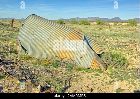 Un vieux réservoir d'eau en acier galvanisé, tombé et rouillé lentement dans le désert de l'Arizona près de Gila Bend. Il est sur une propriété abandonnée dans la fl Banque D'Images