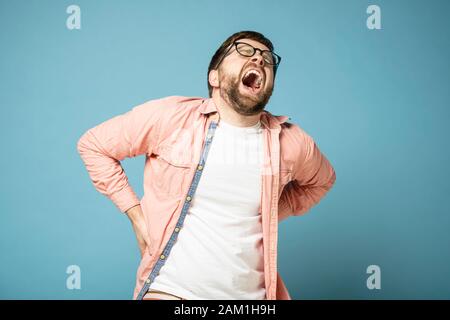 L'homme barbu ressent une douleur très grave dans le bas du dos, il a fermé les yeux de la souffrance, ouvert la bouche large et des cris. Banque D'Images