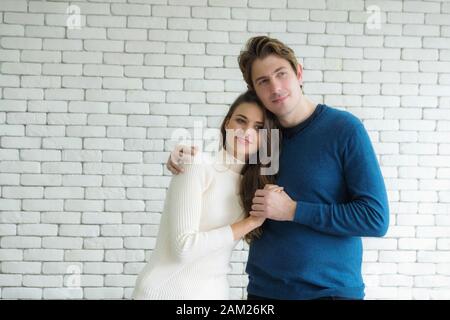 Couples Européens, young man wearing pull bleu et blanc femme portant un chandail, sont debout heureusement hugging les uns les autres dans la chambre. Banque D'Images