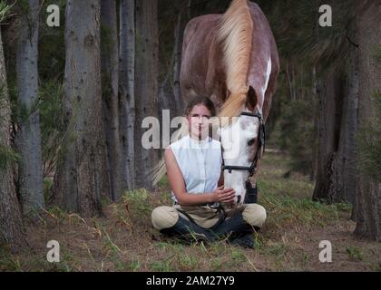 Fille assise devant son cheval de peinture Sabino face à la caméra pleine longueur. Banque D'Images