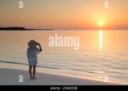 Femme sur banc de sable au coucher du soleil, l'île de Rasdhoo, Nord de Ari Atoll, Maldives Banque D'Images