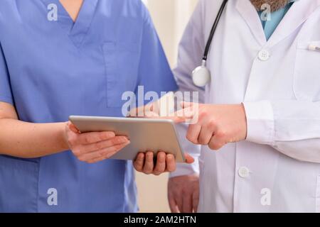 Médecin et infirmière discutant des résultats des tests des patients sur un ordinateur tablette à l'hôpital Banque D'Images