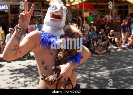 Le participant au défilé de fierté portant un masque unicorn fait le signe de la paix et porte un caniche pour animaux de compagnie, Vancouver Pride Festival 2014, Vancouver, Canada Banque D'Images