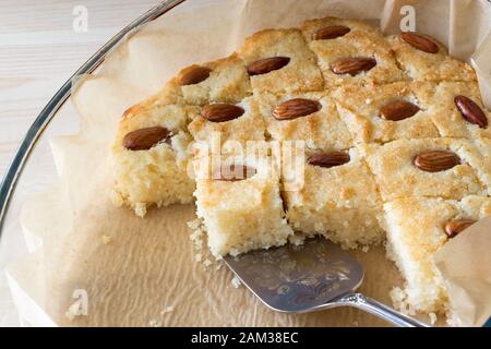 Gros plan de morceaux Basbousa ou Namoora gâteau traditionnel arabe de semoule avec noix d'amande et sirop de rose.Mise au point sélective. Banque D'Images