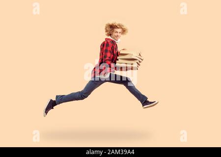 Jeune homme adulte en train de courir avec des boîtes à pizza en carton dans les mains Banque D'Images
