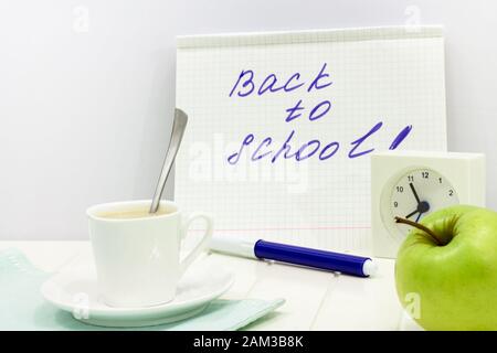 Concept de nouveau à l'école message écrit sur ordinateur portable. Ensemble avec réveil matin, tasse de thé au lait et d'Apple. Copier l'espace. Arrière-plan blanc. Banque D'Images