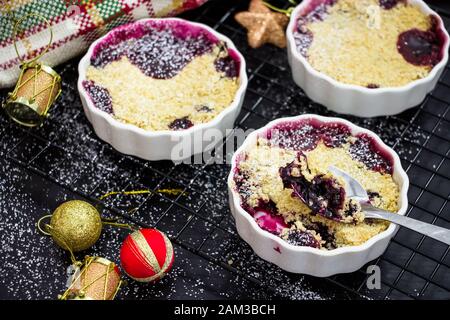 Délicieux crumble maison avec des baies dans des ramequins individuels portés. Petit déjeuner sain. Concept de Noël Banque D'Images