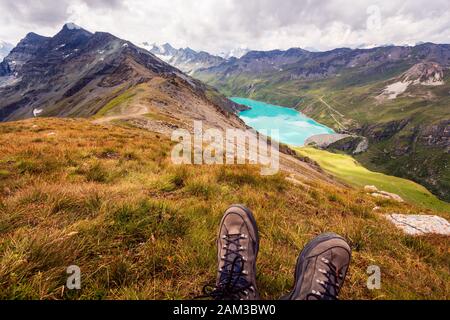 Profitez d'une vue à couper le souffle depuis le sommet d'une montagne sur un lac de montagne. Point de vue de la première personne sur les chaussures de randonnée. Corne De Sorebois, Grimentz, Valais, Banque D'Images