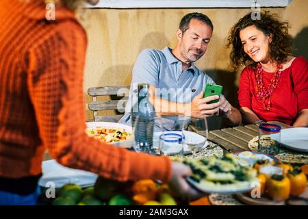 Couple profiter ensemble du contenu de l'appareil cellulaire de smartphone regardant l'écran - les personnes partageant sur les réseaux sociaux - les amis au dîner ensemble un Banque D'Images