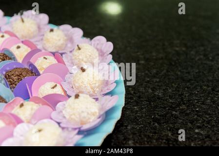 Gros plan sur le plateau avec un jeu de bonbons pour enfants. Bonbons typiques de la fête brésilienne. Bonbons à la noix de coco 'Beizinho' et chocolat 'Brigadeiro'. Mise au point sélective Banque D'Images