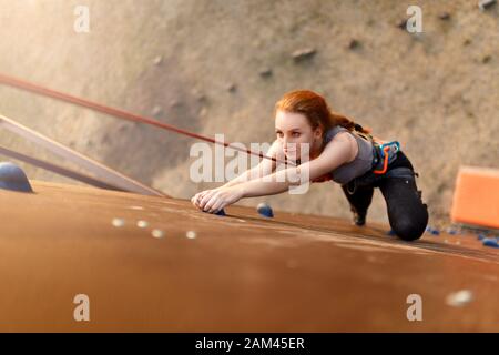 Concept de réussite forte pour les femmes et les entreprises. Jeune femme blanche et jolie pratiquant l'escalade sur mur de roche artificiel à l'extérieur. Petite fille sportive Banque D'Images