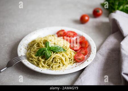 Spaghetti avec sauce pesto fait maison, les feuilles de basilic et les tomates Banque D'Images