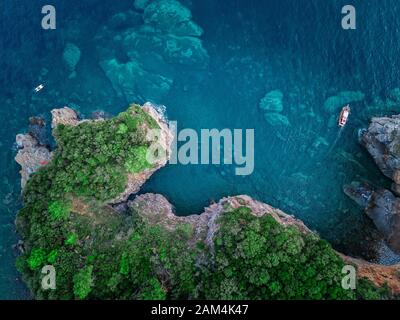 Vue aérienne d'une falaise abrupte et un bateau à moteur. Côte déchiquetée sur la mer Adriatique. Falaises surplombant la mer transparente. Budva, Monténégro Banque D'Images