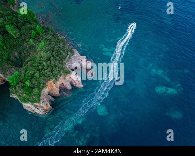 Vue aérienne d'une falaise abrupte et un bateau à moteur. Côte déchiquetée sur la mer Adriatique. Falaises surplombant la mer transparente. Budva, Monténégro Banque D'Images