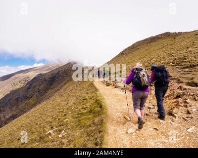 Les randonneurs randonnée sur chemin sur Rhyd Ddu Bwlch principal avec vue de nuages bas sur le mont Snowdon au sommet du Parc National de Snowdonia, Gwynedd, au nord du Pays de Galles, Royaume-Uni, Angleterre Banque D'Images