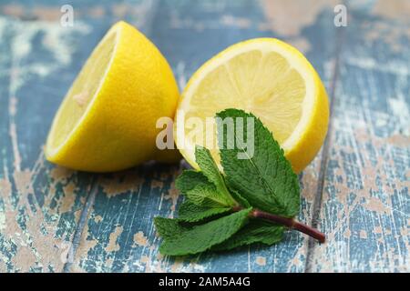 Feuilles de menthe fraîche et deux moitiés de citron juteux sur une surface rustique en bois Banque D'Images