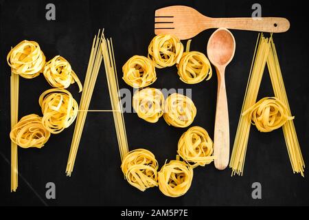 Un mot PÂTES avec spaghetti brut et tagliatelle boules rondes de pâtes sur le fond noir Banque D'Images