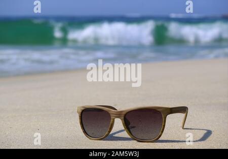 Lunettes de soleil sur la plage avec vagues floues en arrière-plan Banque D'Images