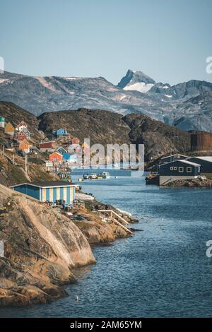 Des maisons colorées parsement les collines de la ville de pêcheurs de Kangaamiut, à l'ouest du Groenland. Icebergs du glacier de Kangia au Groenland nageant avec le ciel bleu Banque D'Images