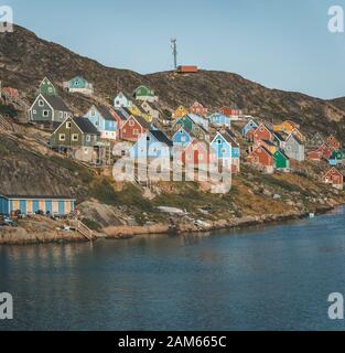 Des maisons colorées parsement les collines de la ville de pêcheurs de Kangaamiut, à l'ouest du Groenland. Icebergs du glacier de Kangia au Groenland nageant avec le ciel bleu Banque D'Images