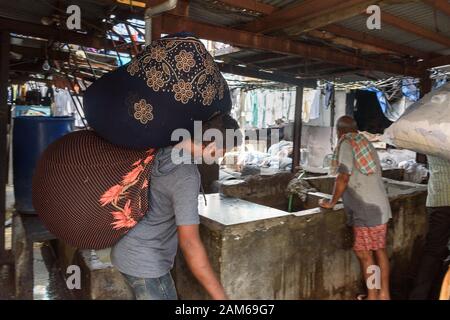 Le woker indien transportant des sacs de vêtements à Dhobi Ghat est une blanchisserie extérieure à Mumbai. Inde Banque D'Images