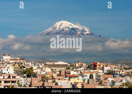 Mont Chimborazo volcan (6268 m) vu à travers les toits de la ville de Riobamba. Banque D'Images