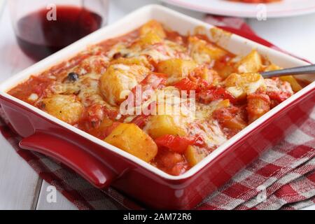 Ragoût végétarien avec pomme de terre, poivron, carotte, et le fromage râpé dans un plat allant au four, sur une table rustique Banque D'Images