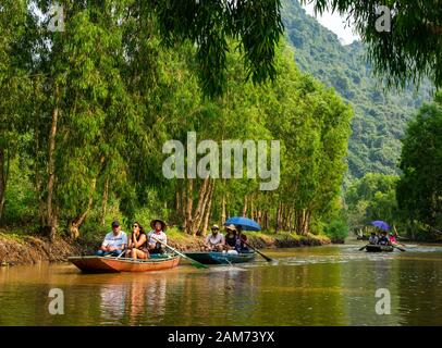 Les touristes dans les sampans rongé par les Asiatiques locaux aviron avec des pieds, Tam Coc, Ninh Binh, Vietnam, Asie Banque D'Images