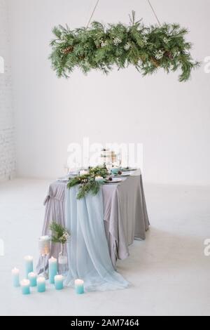 Belle table décorée avec des bougies bleues, des pins, des fleurs et des gâteaux de mariage sur la table en studio Banque D'Images