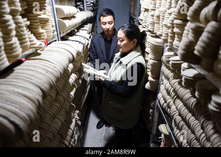 (200112) -- GANGU, 12 janvier 2020 (Xinhua) -- Guo Juan et son mari Niu Junjun vérifient la qualité des semelles à l'usine du comté de Gangu, dans le nord-ouest de la province de Gansu en Chine, 10 janvier 2020. NIU Junjun, né en 1987 à Gangu, a commencé la chaussure avec sa femme Guo Juan à la suite d'une histoire d'amour. NIU et Guo étaient des copains d'université dont l'histoire d'amour a commencé avec une paire de chaussures de chanvre Gangu, un patrimoine provincial immatériel de la ville natale de Niu. "Les chaussures d'été confortables et fraîches de chanvre Niu m'ont amené à augmenter mon affection pour lui et puis nous sommes tombés dans l'amour", a rappelé Niu. Cette spe Banque D'Images