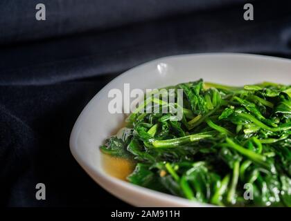 De délicieux légumes verts sautés sur une plaque sur fond noir, plats de gros plan. Banque D'Images