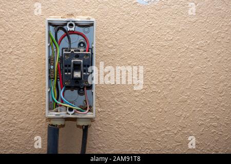 Boîtier électrique extérieur résidentiel devant être réparé avec des fils et des interrupteurs exposés. Bricolage, réparation, entretien. Espace de copie. Banque D'Images
