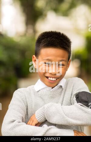 Portrait d'un jeune garçon asiatique souriant à l'extérieur. Banque D'Images