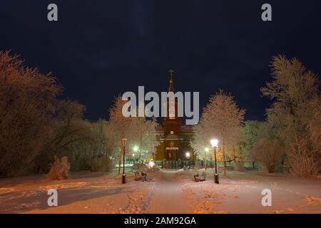 La construction de l'église orthodoxe la nuit entourée d'arbres dans la neige. Banque D'Images